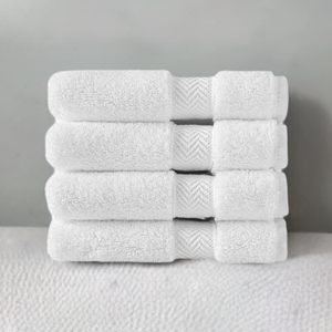 Soft white SaaSoh Klassic Collection bath towels folded on a wooden surface, showcasing plush texture and high-quality fabric.